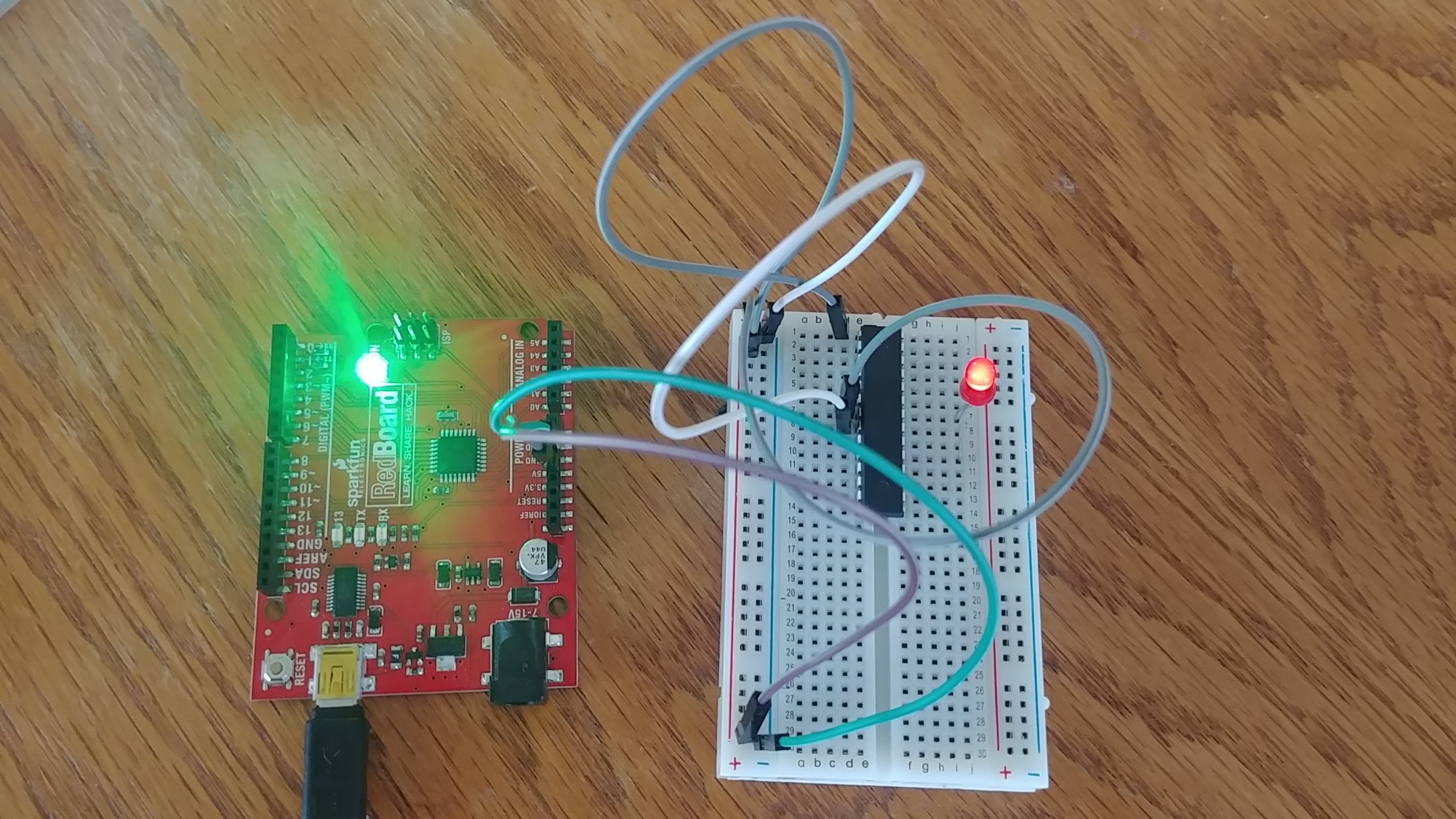 The ISP is next to the breadboard with the atmega328. the ISP is providing power, but no other connections. The breadboard has multiple wires on it and a single LED